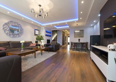 Modern living room with led ceiling lights, hardwood floors, and contemporary furniture.