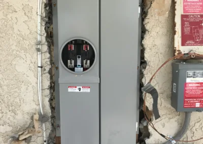 An electrical panel installed on an unfinished wall with exposed wires and cables.