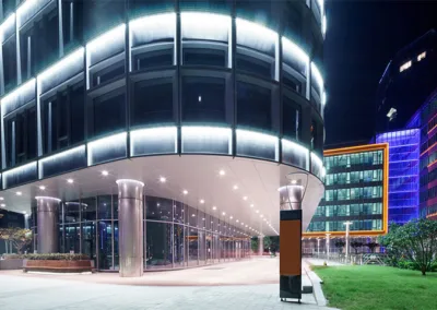 Modern office building illuminated at night with a pedestrian walkway.